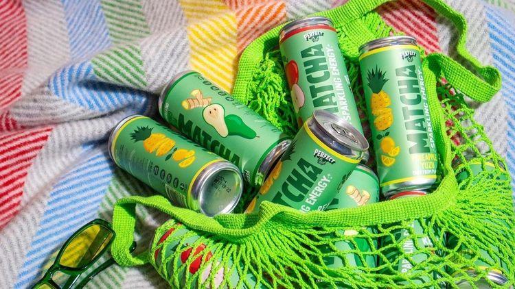 green cans of mach drink lying on a rainbow coloures surface in a green net bag
