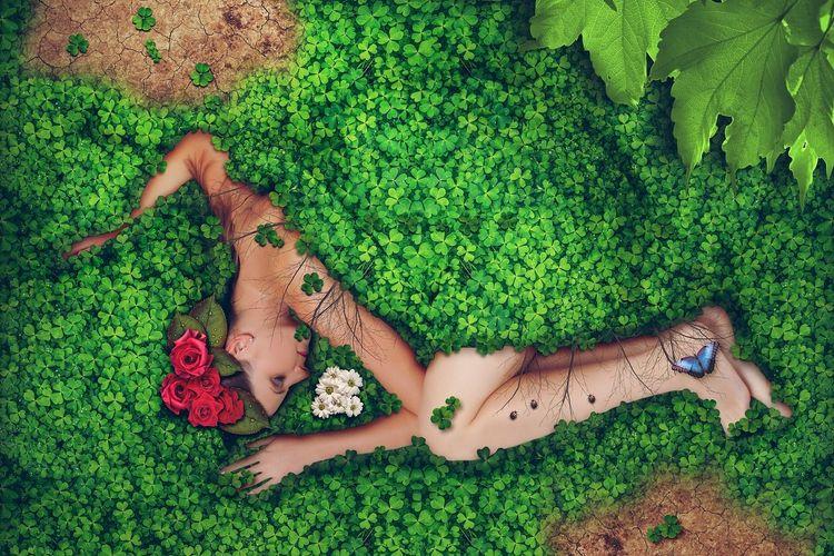 Woman laying on the ground covered in plants, flowers and a butterfly.