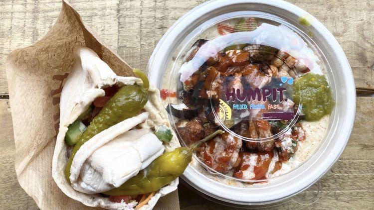 A Humpit Sheffield’s filled pita next to a Humpit hummus bowl, both are filled with salad toppings and covered in sauces.