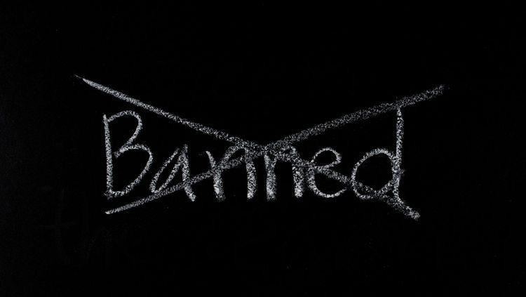 The word ‘banned’ written in white chalk banned crossed out on a blackboard