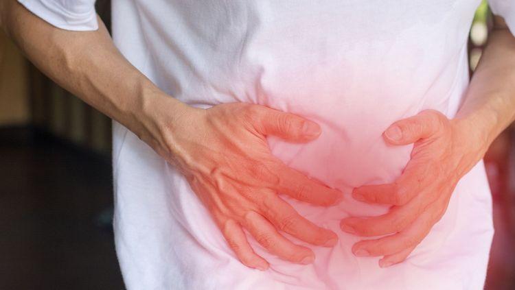 Man having abdominal pain and holding his stomach as he is suffering with Crohn’s disease