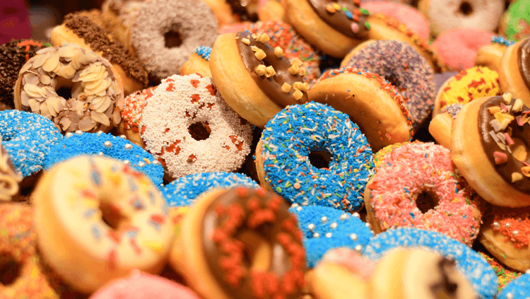Variety of multicoloured ring vegan doughnuts with a variety of toppings such as sprinkles and almonds