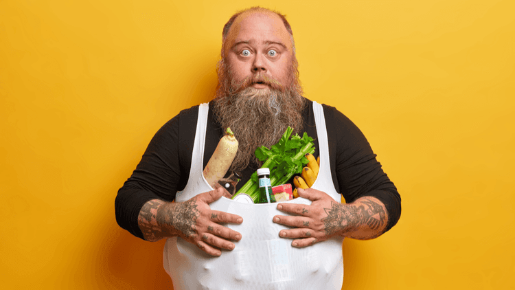 Surprised-looking man with a long beard and a white apron full of vegetables on an orange background