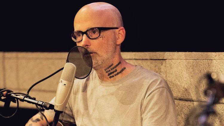  Moby singing into a microphone and playing guitar