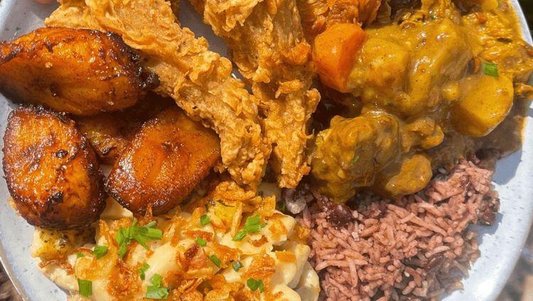 Variety of vegan Jamaican food from Aizzy’s, includes: fried plantain, ‘vegan goat’, rice, coleslaw and gravy