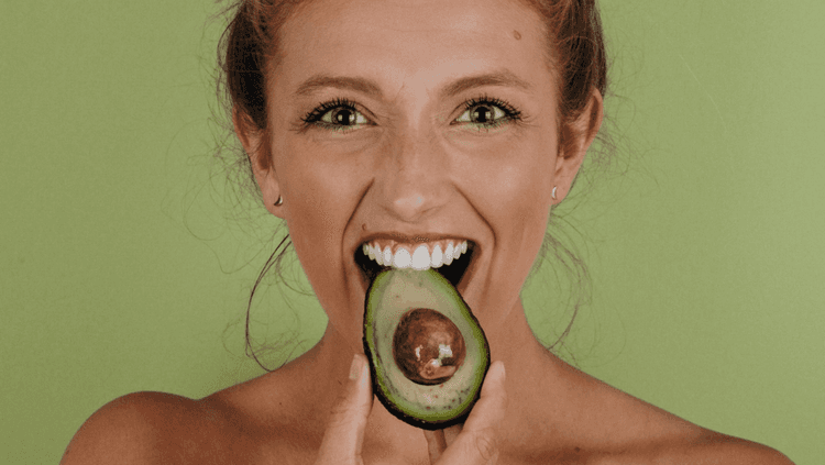 Woman nibbling on an avocado